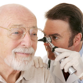Doctor using otoscope to look in a senior man's ears. Closeup on white. Focus on doctor.